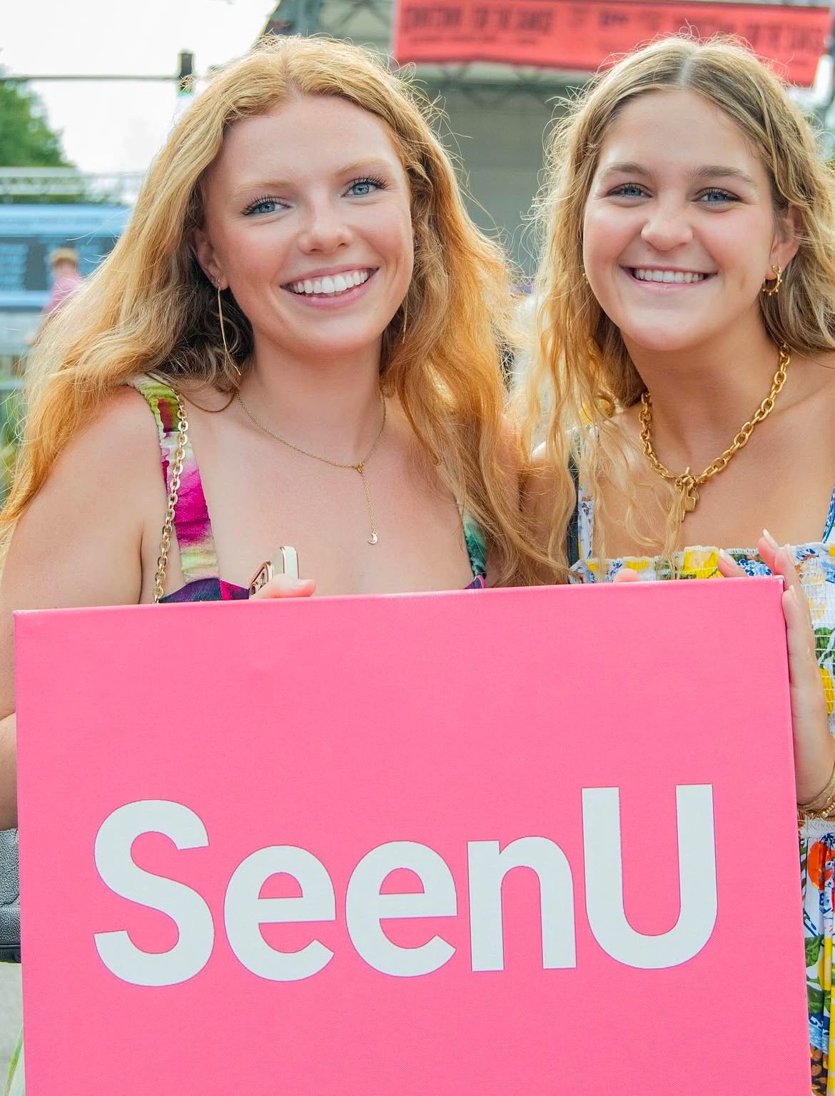 Two Girls Holding a SeenU placard